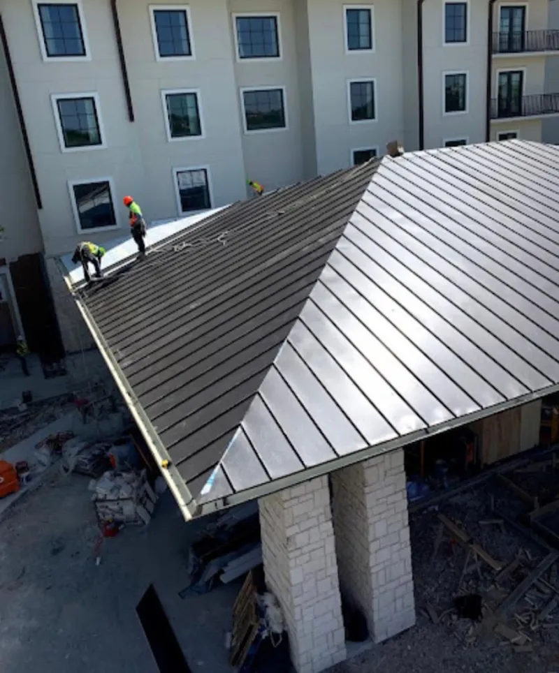 Crew installing standing seam metal roof panels on a commercial project in Radford